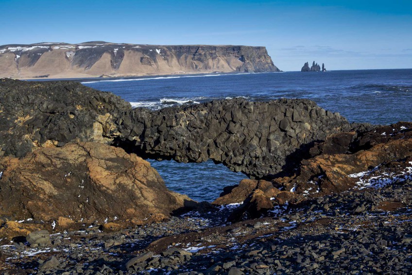 Basaltsäulen-Brücke mit den drei Felsnadeln Reynisdrangar im Hintergrund.